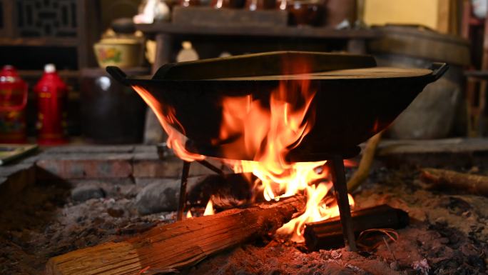 乡村火塘里燃烧的木头和铁架上的锅