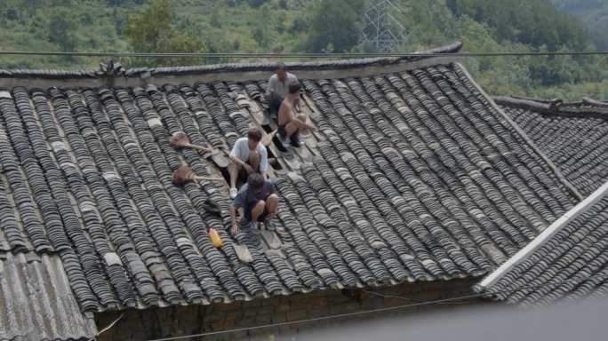 农民在屋顶捡瓦片维修瓦房