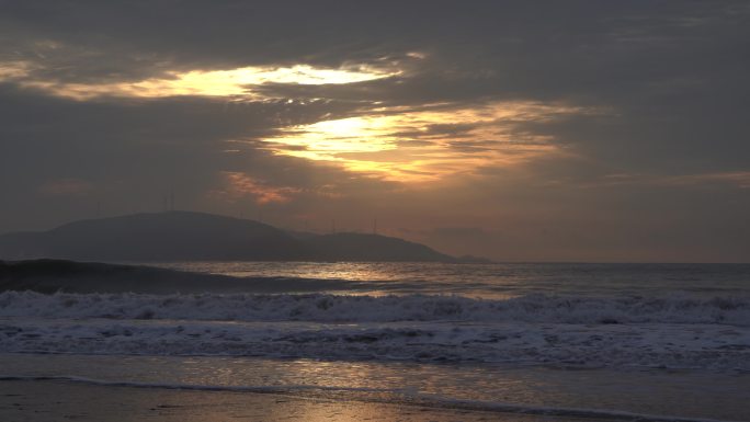 沙滩上的日出金光闪烁潮水涌动海浪翻腾