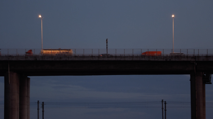4k 夜幕降临远处桥上的车 海上列车经过