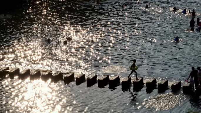 夕阳撒在水面波光粼粼亲子游泳剪影欢乐