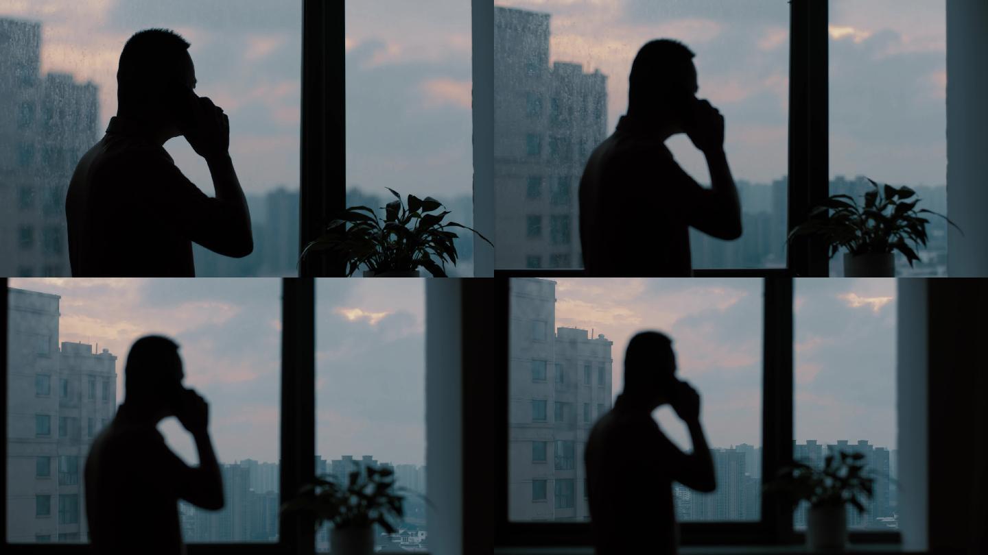 男人在窗前打电话的剪影