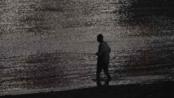 长江边的夜钓者，站在江水里甩杆钓鱼