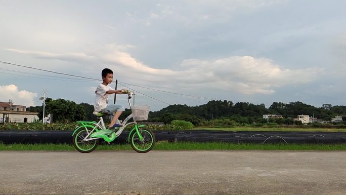 乡村傍晚小孩骑自行车乡村孩子顽皮乡间骑车