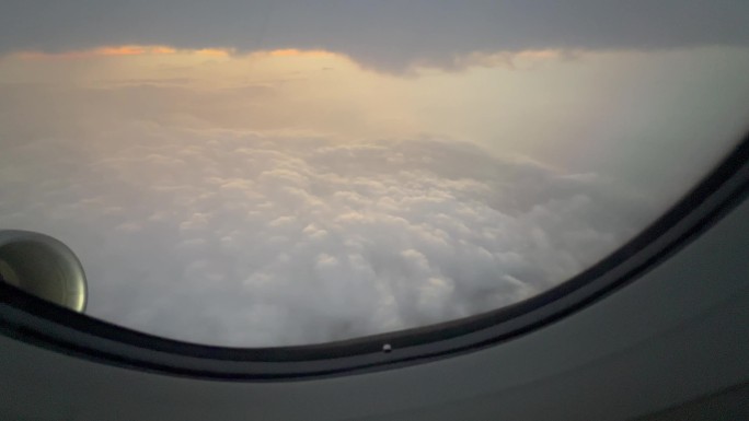 穿越云层的飞机舷窗外的傍晚自然风光