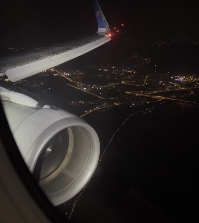 飞机舷窗外夜晚现代城市风光和机翼
