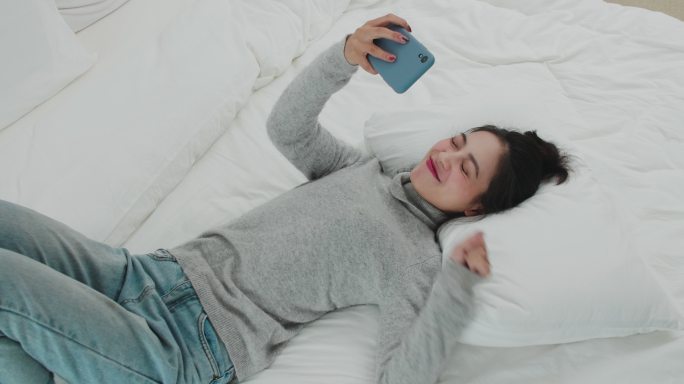 美女下班躺在床上用手机和朋友视频聊天
