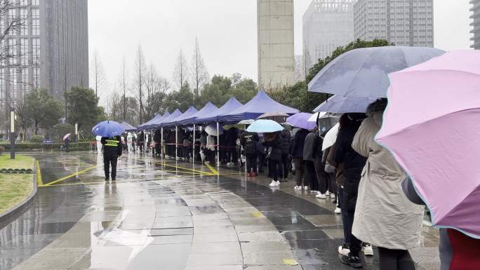 下雨天市民排队在城市广场上做核酸