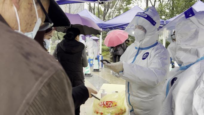 下雨天市民排队在城市广场上做核酸