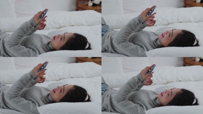美女躺在床上看手机放松休闲
