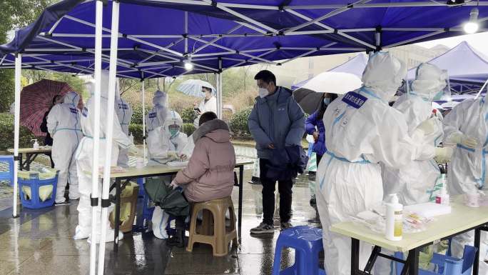 市民在雨棚下排队做核酸