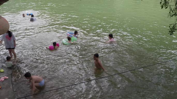 河边玩水游泳家长看护孩子在河里游泳