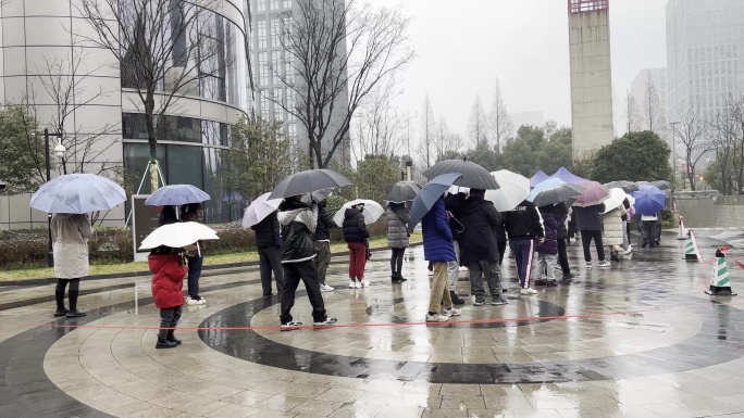 下雨天市民排队在城市广场上做核酸