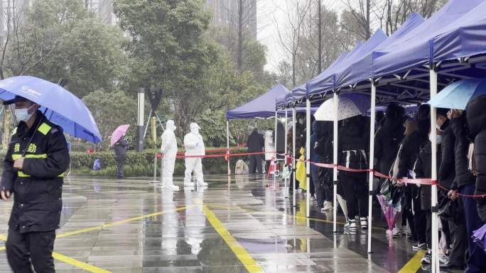 下雨天市民排队在城市广场上做核酸