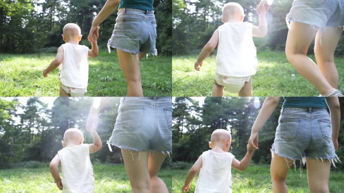 母子手牵手婴儿学步婴儿第一次走路草地迈步