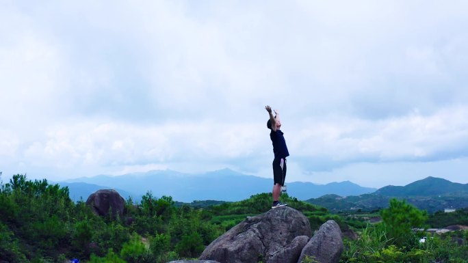 站在山顶向着天空举起双臂航拍