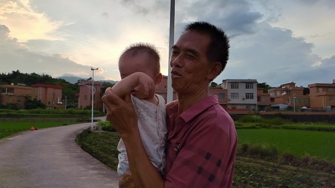 村民村庄田间田野农民大叔抱着孩子的笑脸
