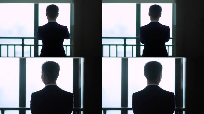 站在窗前沉思的商务男性背影