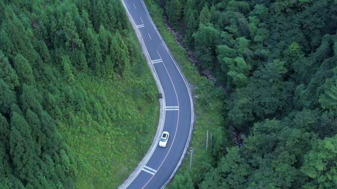 俯视山林蜿蜒公路后飞白色行车