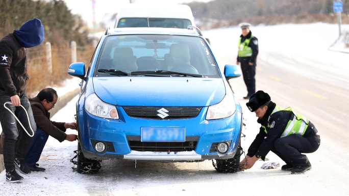 冬季雪中交警协助出租车司机安装防滑链