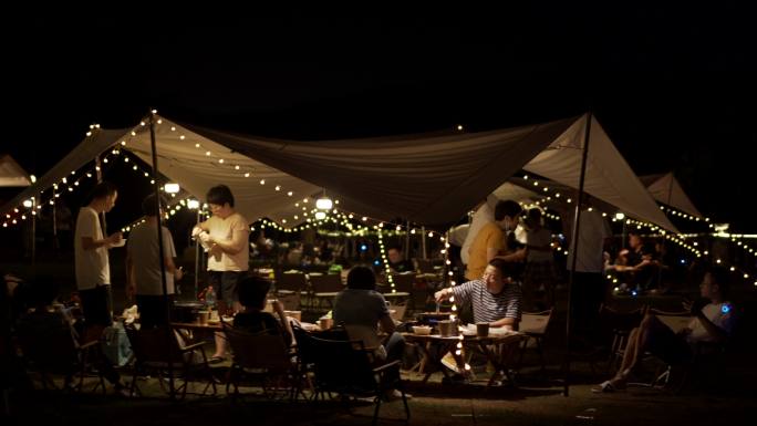 夜晚一群人打着天幕露营野餐
