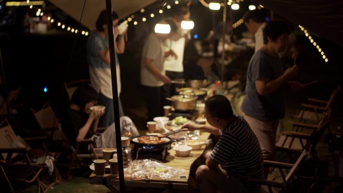 夜里露营准备晚餐烤肉的一家人