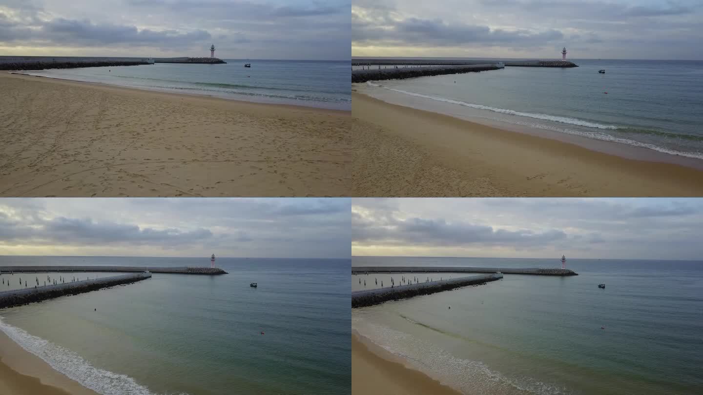 清晨海边堤岸上的灯塔与渔船