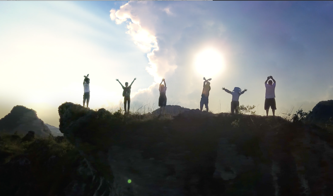 一群人逆光登顶成功 站在山顶举手环湖庆祝