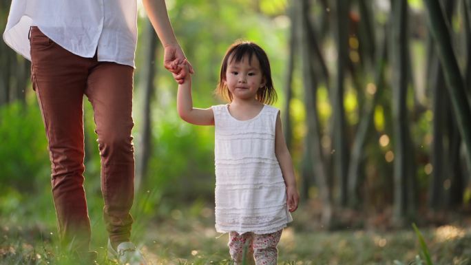 欢乐亲子时光小女孩牵着妈妈的手在公园散步