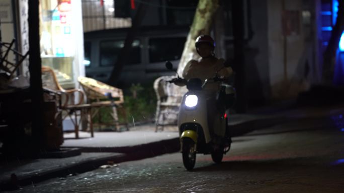 秋夜雨天城市小巷路人行人电瓶车冒雨回家