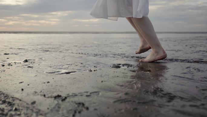 女孩光脚奔跑在海边滩涂上