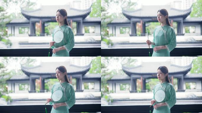 身穿汉服年轻女子站在中式合院景观池摇扇子
