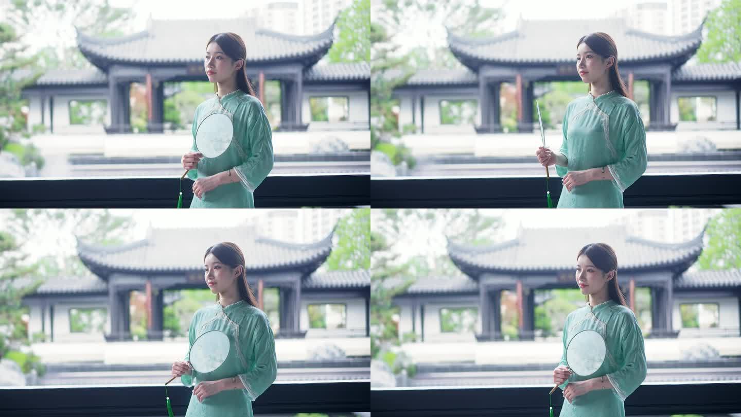身穿汉服年轻女子站在中式合院景观池摇扇子