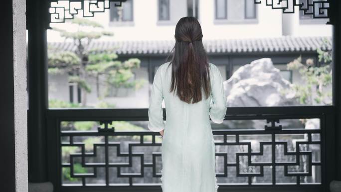 身穿汉服年轻女子走到中式合院回廊栏杆边