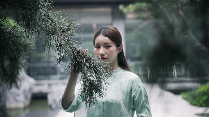 汉服年轻女子在园林景观松树前闻一闻清香