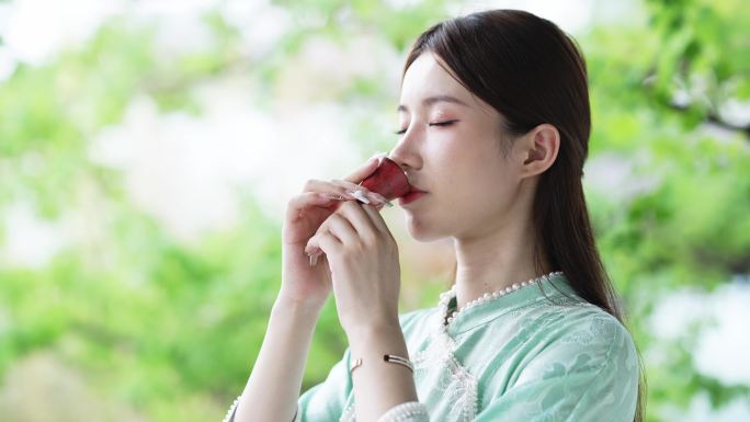 身穿汉服年轻女子在院子里端起茶杯喝茶