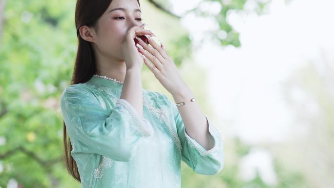 身穿汉服年轻女子在院子里端起茶杯喝茶