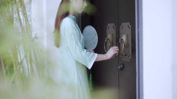 年轻旗袍女子摇着扇走到中式合院门前敲门