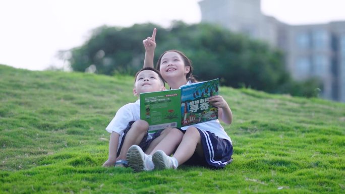 两个孩子在公园草地看书，眺望远方