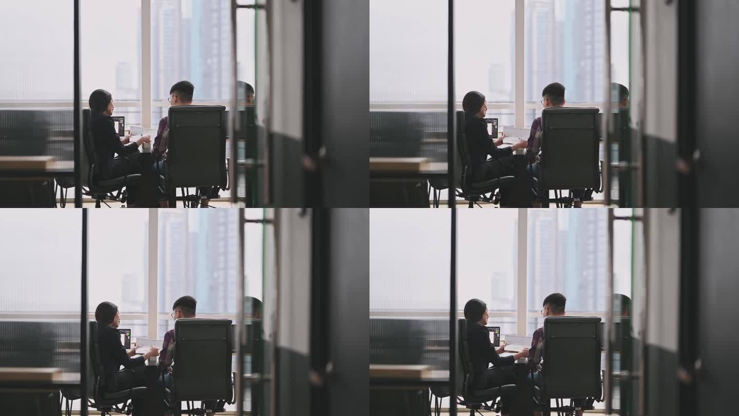 后视图：一位亚裔中国女同事在办公室向她的学员解释讨论
