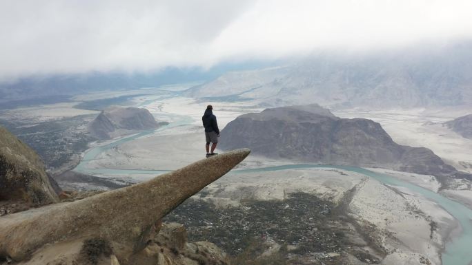 一个人站在岩石上，看着喜马拉雅山上的河流
