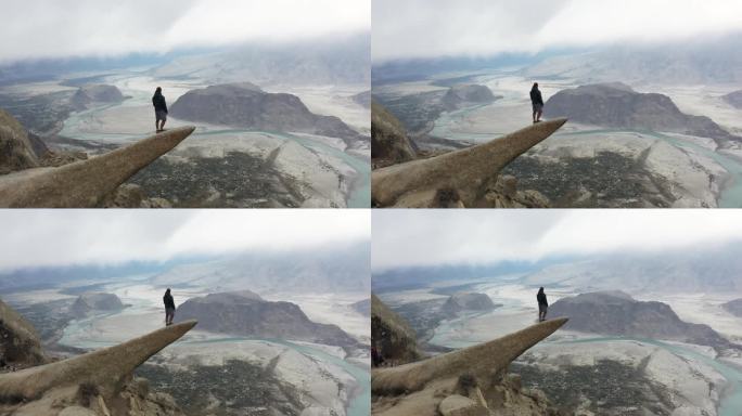 一个人站在岩石上，看着喜马拉雅山上的河流