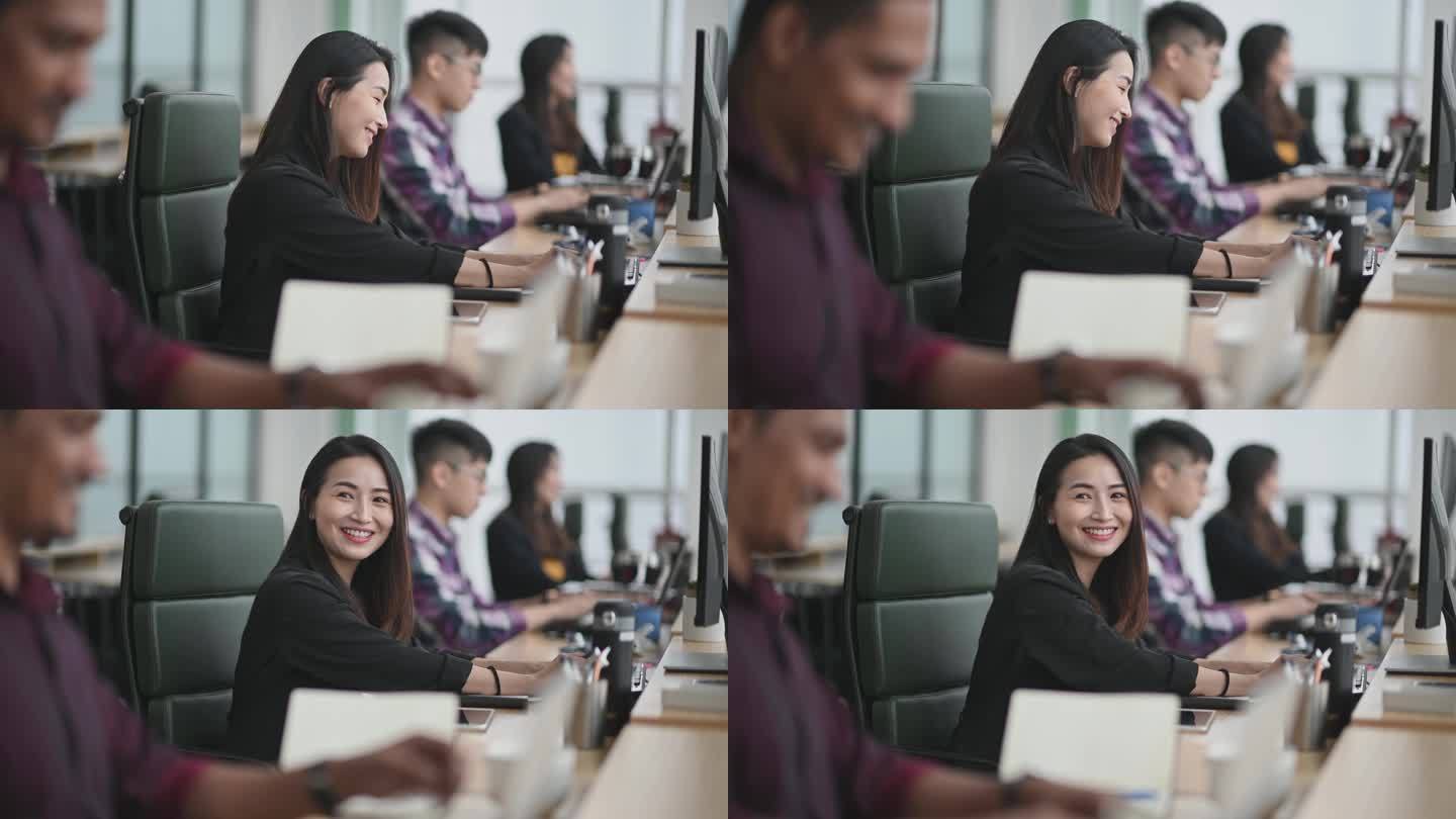 美丽的亚裔中国妇女微笑着在她的工作场所与同事交谈