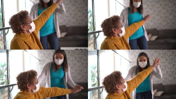 物理治疗师正在帮助一位老年妇女在家里做运动-使用防护面罩
