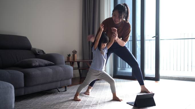 母亲和女儿在家里上在线瑜伽课