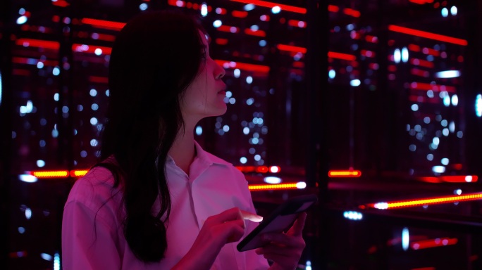 一名亚洲少女在黑暗的夜晚在五颜六色的紫外线照明下使用5G移动智能手机。移动互联网，新一代网络。可视化