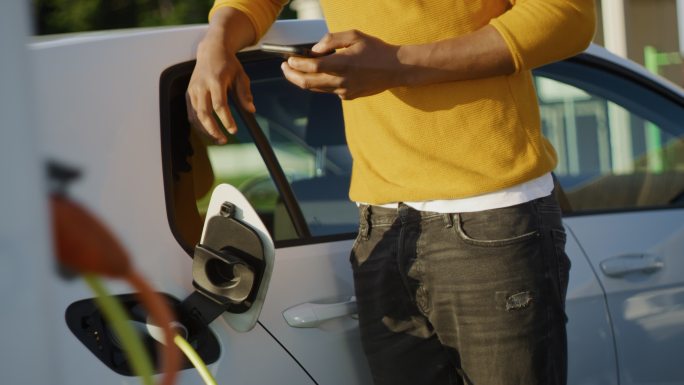 斯洛·莫：一个年轻人在停车场给他的车充电时使用他的智能手机