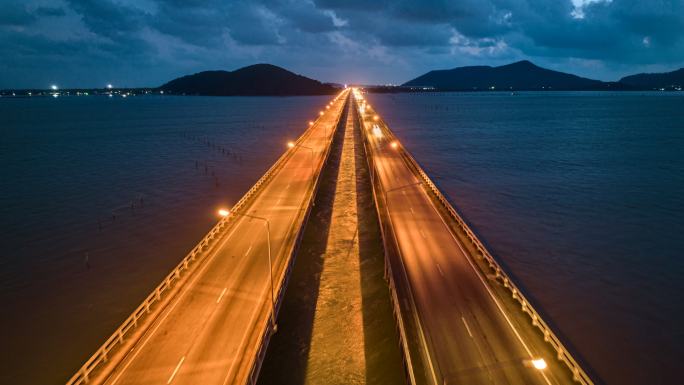 空中无人机超延时或延时夜景，Tinsulanonda大桥松克拉湖大桥上的交通车。泰国松克拉湖桥沿线