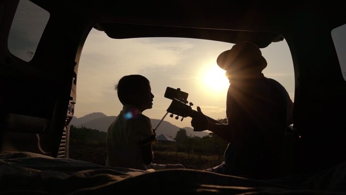 亚裔父亲和儿子在车后。社交媒体上的实时流媒体在自然中放松。周末旅行。