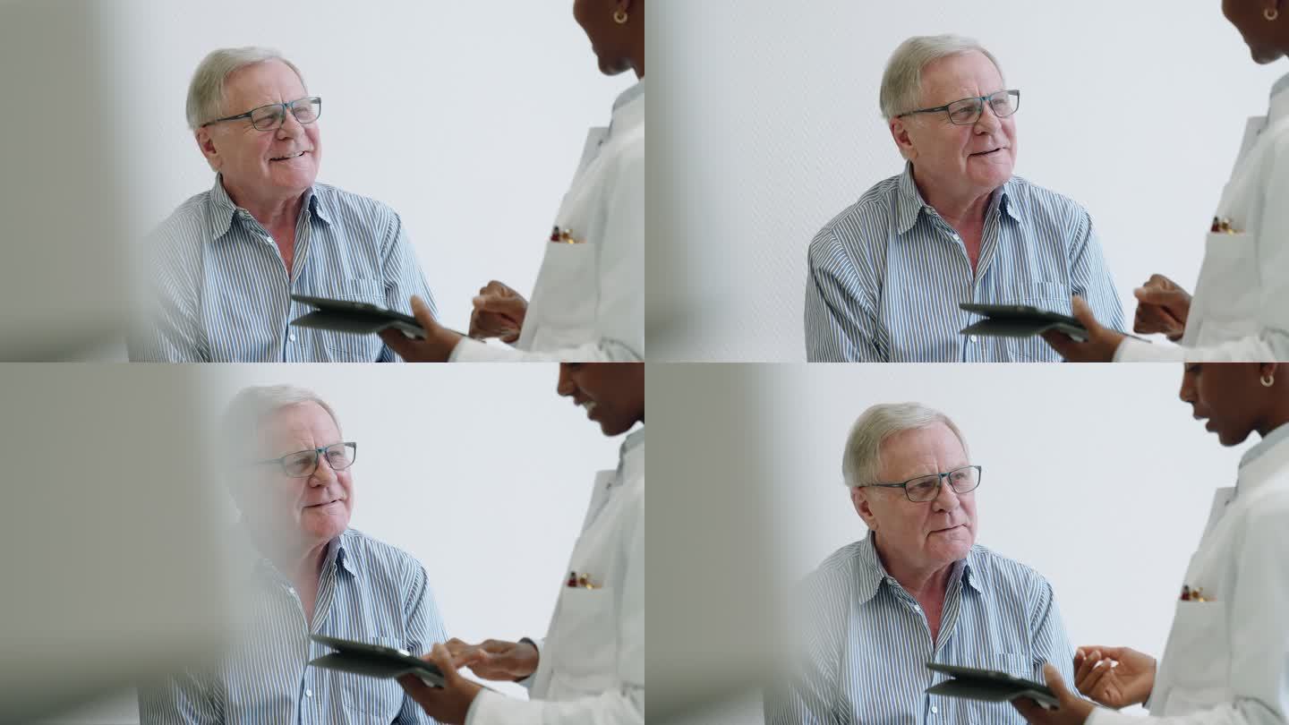 老年男性患者与医生讨论使用数字平板电脑